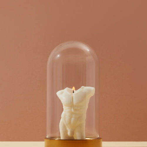 One white candle with faceless male shape burning with flame under glass lid on brown background with copy space